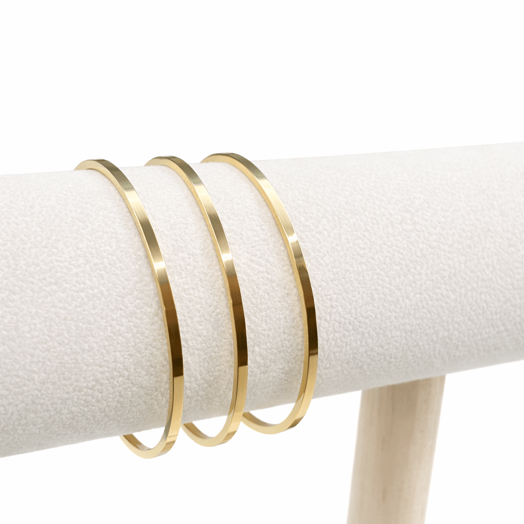 Three gold bangles on a white surface