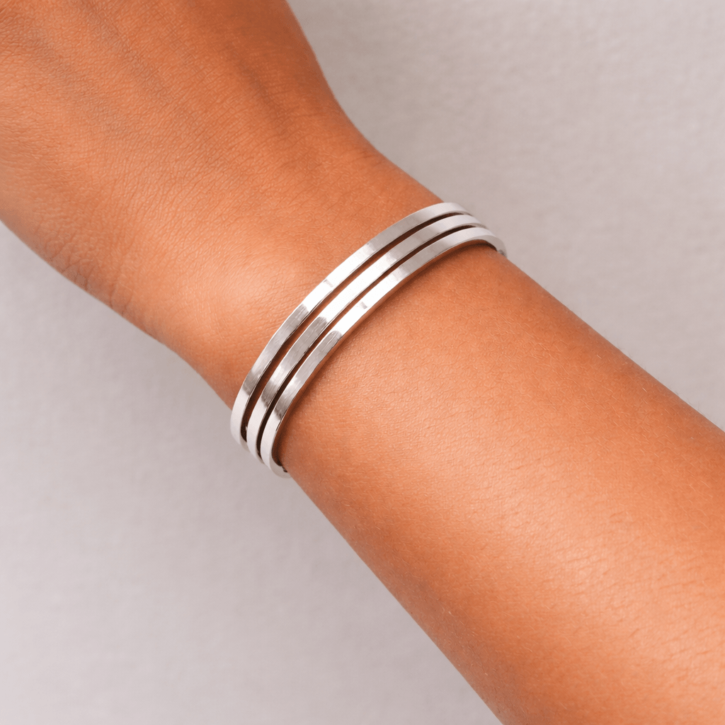 Silver bracelet on a person's wrist against a neutral background