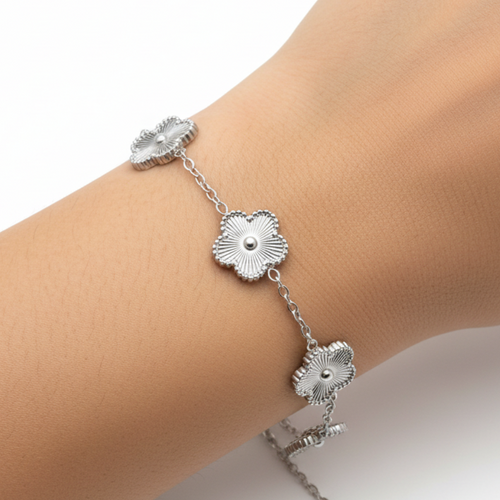 Silver bracelet with floral designs on a wrist against a white background