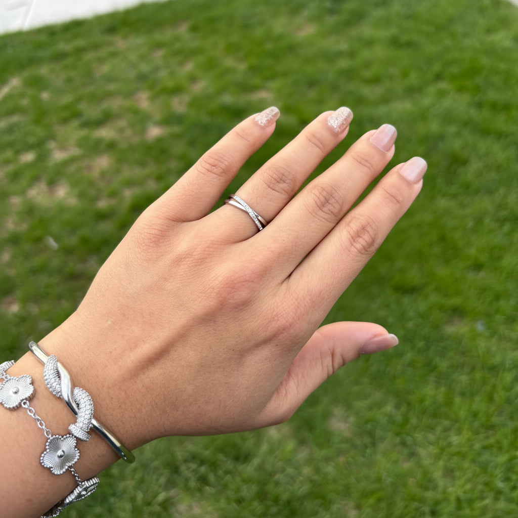 Hand with a ring and bracelet against a grassy background