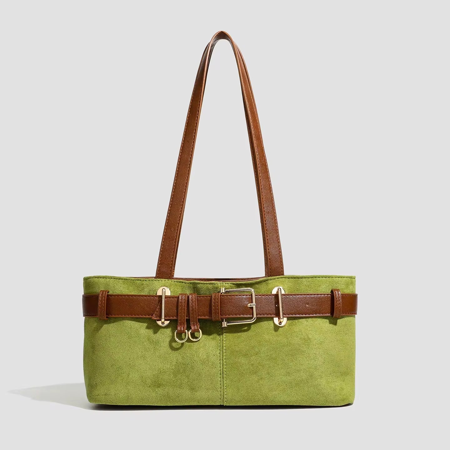 Green tote bag with brown leather straps and belt on a light gray background